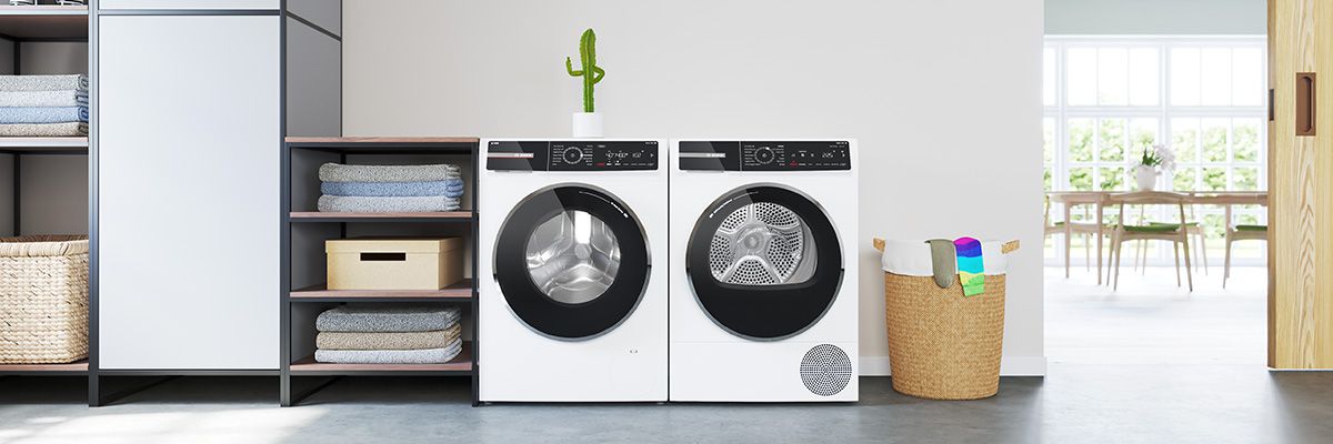 Moderne Waschmaschine im Hauswirtschaftsraum, umgeben von Regalen und Reinigungsmitteln, gut beleuchtet und funktional.